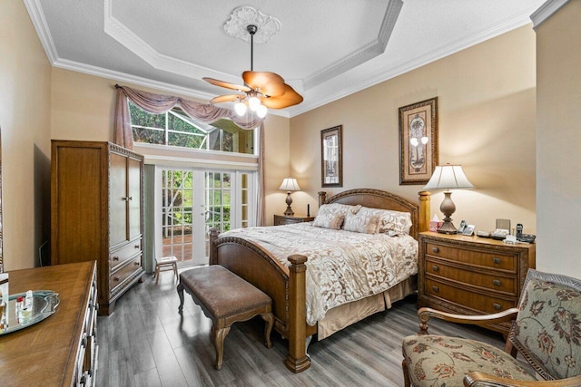 bedroom with ceiling fan, a raised ceiling, dark hardwood / wood-style floors, and access to exterior