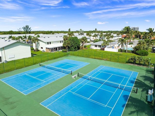 view of sport court with fence, a yard, and a residential view