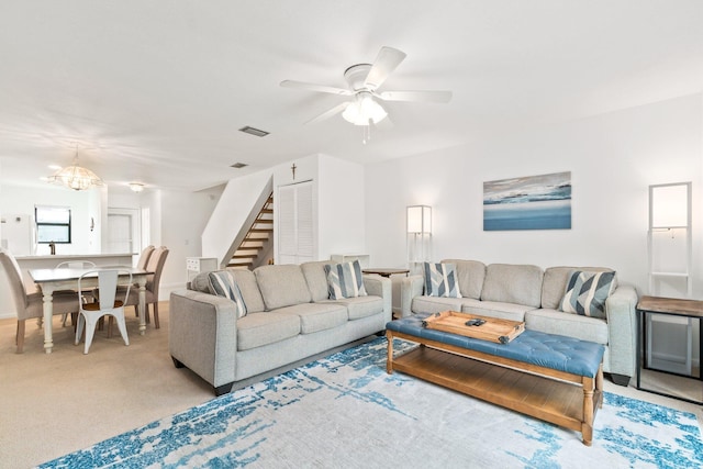 carpeted living area with visible vents, ceiling fan, and stairway