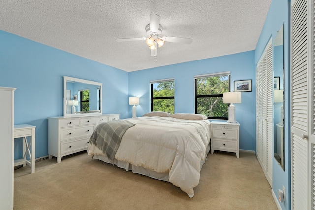 carpeted bedroom with ceiling fan and a textured ceiling