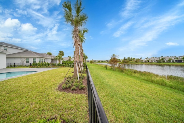 view of swimming pool with a patio area, a yard, and a water view