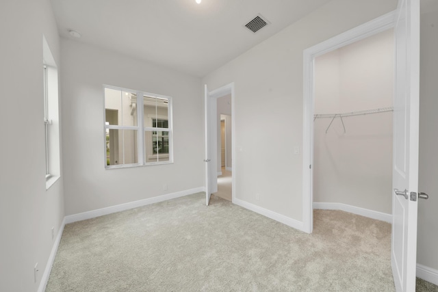 unfurnished bedroom with light colored carpet and a closet