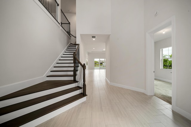 staircase featuring a towering ceiling and carpet flooring