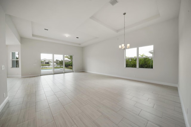 unfurnished room featuring a chandelier and a tray ceiling