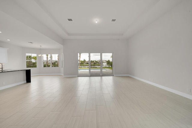 empty room featuring an inviting chandelier and a raised ceiling