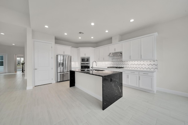 kitchen with appliances with stainless steel finishes, white cabinets, sink, and an island with sink