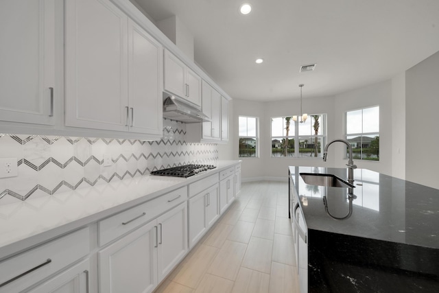 kitchen with sink, white cabinetry, dark stone countertops, decorative backsplash, and a chandelier