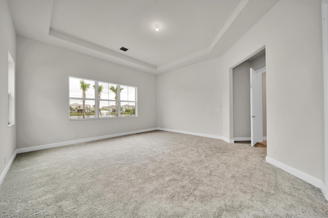 empty room with a tray ceiling and light colored carpet