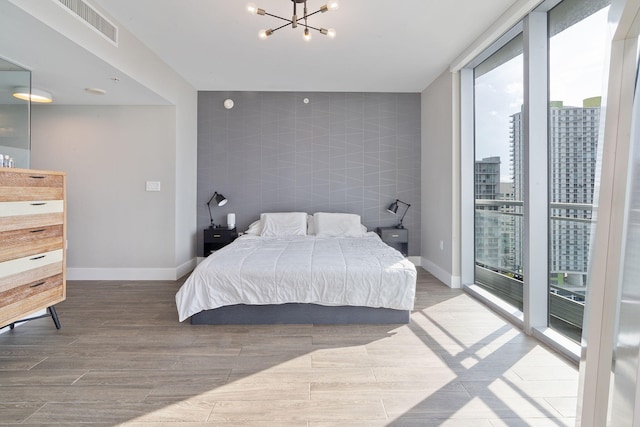 bedroom featuring tile walls, access to exterior, an inviting chandelier, and hardwood / wood-style flooring