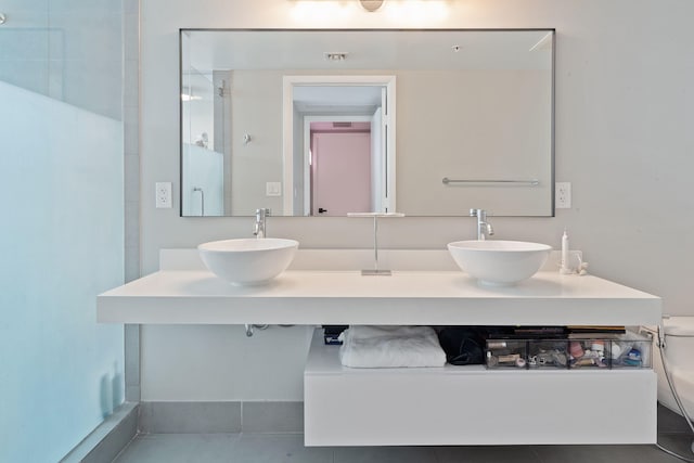 full bath featuring double vanity, tile patterned floors, toilet, and a sink