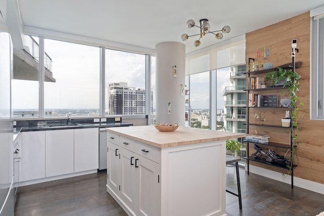 kitchen with a kitchen island, wood counters, white cabinets, a breakfast bar area, and a chandelier