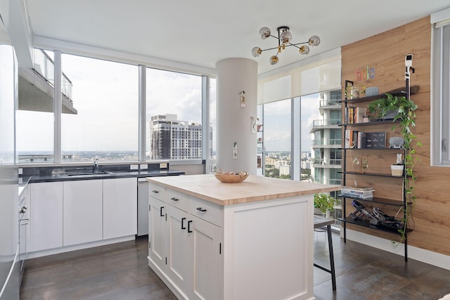 kitchen featuring a center island, a sink, butcher block countertops, white cabinetry, and a breakfast bar