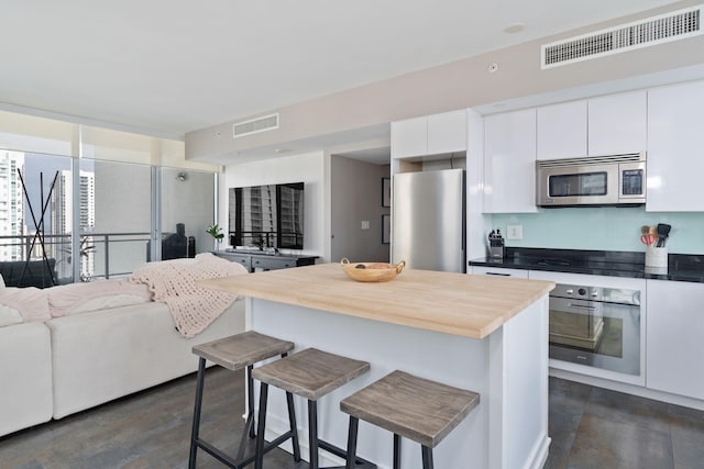 kitchen with a breakfast bar, visible vents, appliances with stainless steel finishes, and open floor plan