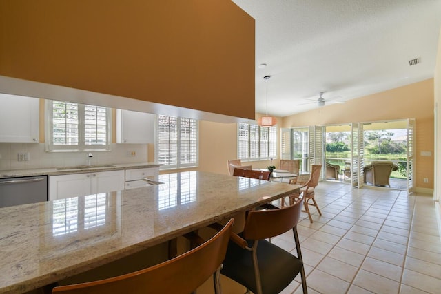 kitchen featuring sink, hanging light fixtures, light stone counters, stainless steel dishwasher, and white cabinets