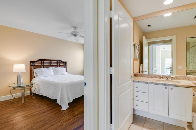 bedroom featuring ceiling fan, sink, and light hardwood / wood-style flooring