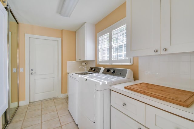 washroom featuring washer and dryer, light tile patterned floors, and cabinets