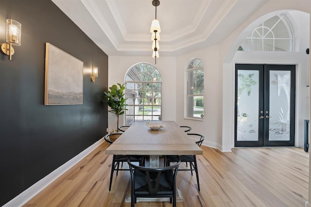 dining area with light hardwood / wood-style flooring, french doors, a tray ceiling, and crown molding