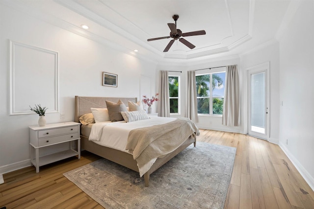 bedroom with light hardwood / wood-style flooring, a raised ceiling, access to outside, and ceiling fan