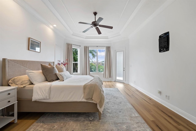 bedroom with ceiling fan, ornamental molding, a tray ceiling, and hardwood / wood-style floors