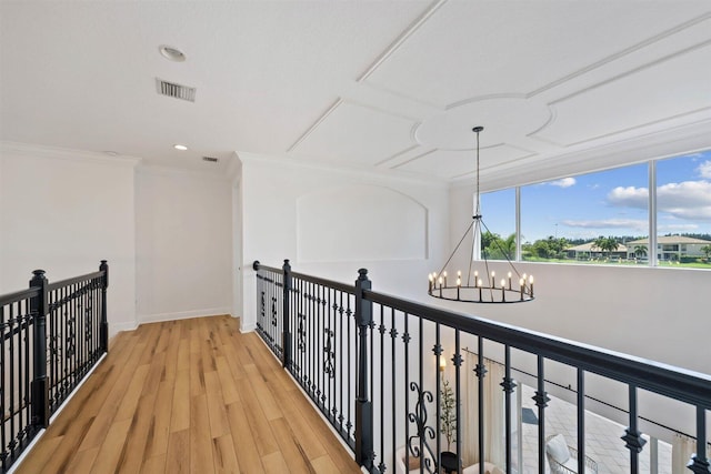 hallway with light hardwood / wood-style floors, a notable chandelier, and crown molding