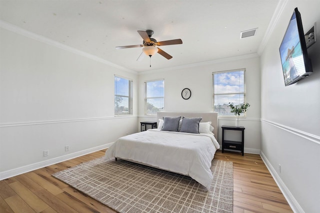 bedroom with multiple windows, wood-type flooring, crown molding, and ceiling fan