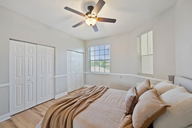 bedroom with light hardwood / wood-style flooring, multiple closets, and ceiling fan