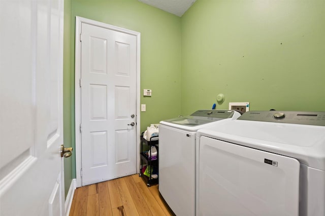 laundry room featuring light hardwood / wood-style flooring, a textured ceiling, and washing machine and dryer