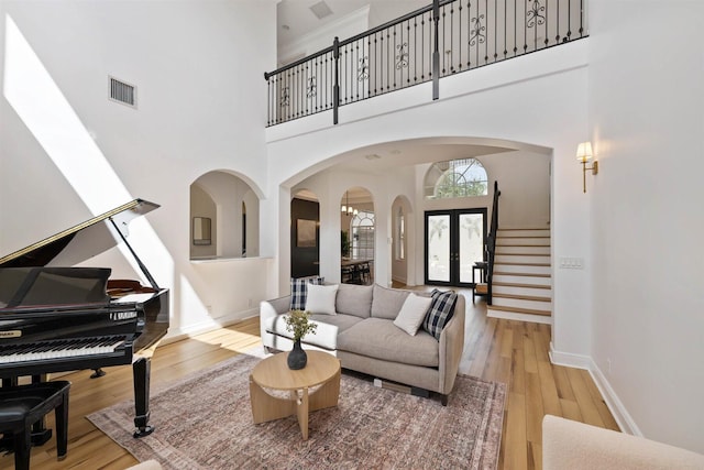 living room with french doors, hardwood / wood-style flooring, and a towering ceiling