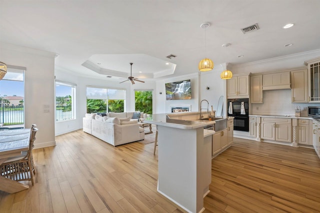 kitchen with sink, light wood-type flooring, cream cabinets, and plenty of natural light