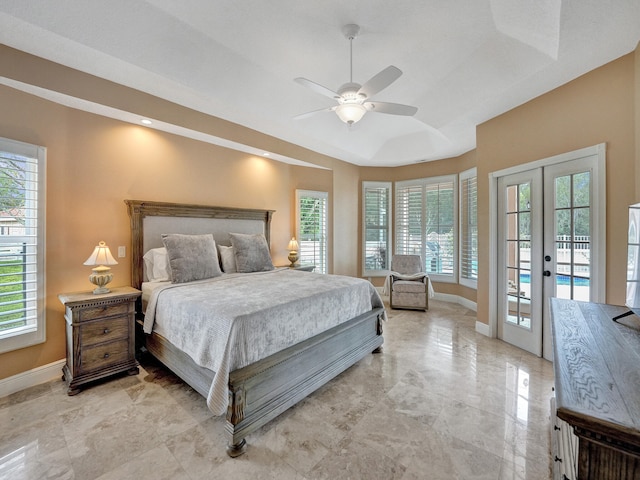 bedroom featuring french doors, a tray ceiling, multiple windows, and access to outside