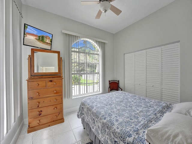 tiled bedroom featuring ceiling fan and a closet