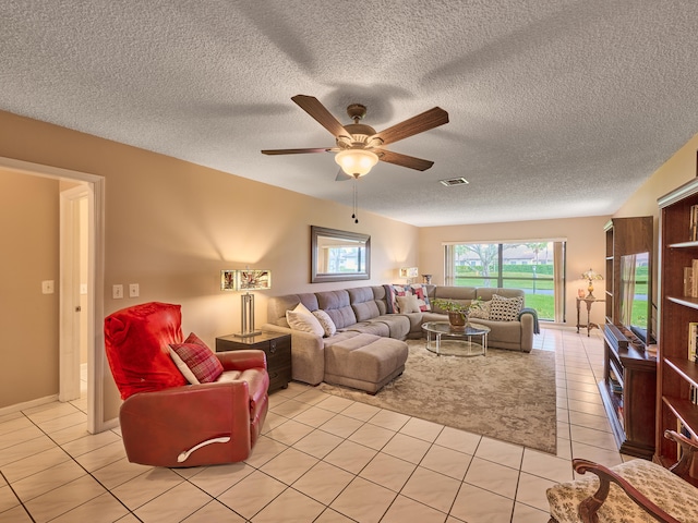 living room featuring a textured ceiling, light tile patterned floors, and ceiling fan