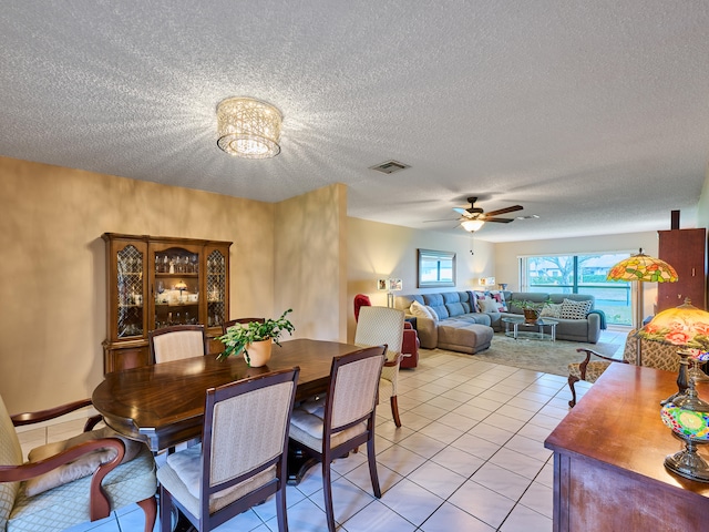 tiled dining space featuring a textured ceiling and ceiling fan