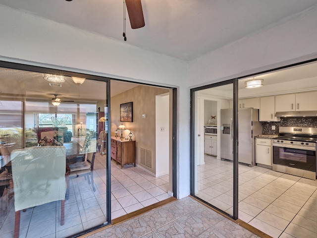 interior space featuring tasteful backsplash, appliances with stainless steel finishes, light tile patterned floors, and ceiling fan