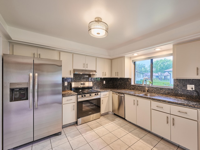 kitchen with stainless steel appliances, dark stone counters, sink, and tasteful backsplash