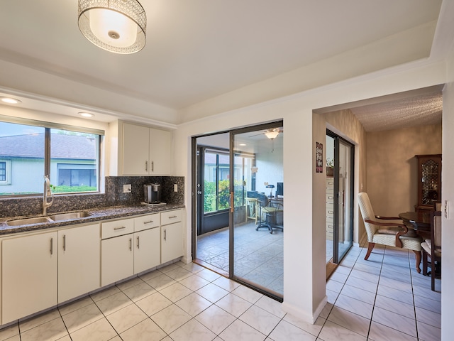 kitchen featuring dark stone countertops, white cabinetry, a wealth of natural light, and sink