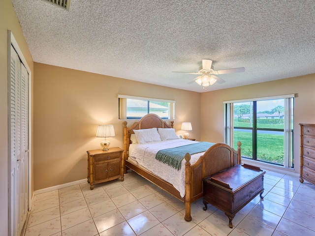 bedroom with a textured ceiling, ceiling fan, and a closet