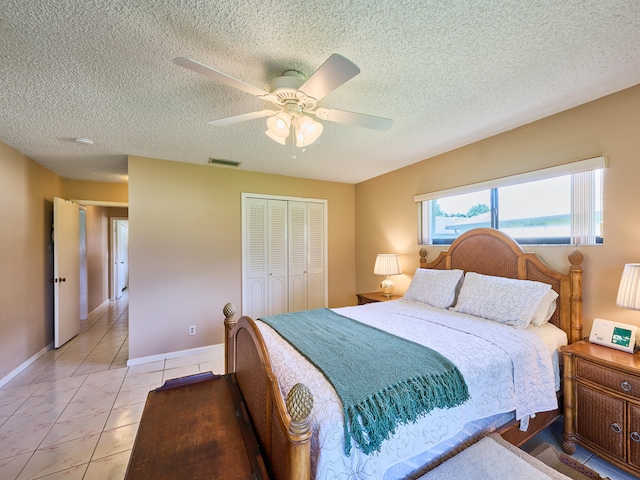 tiled bedroom with a closet, a textured ceiling, and ceiling fan