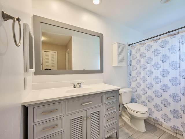 bathroom with toilet, vanity, and curtained shower