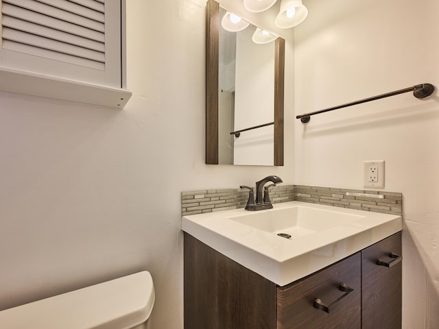 bathroom with toilet, tasteful backsplash, and vanity