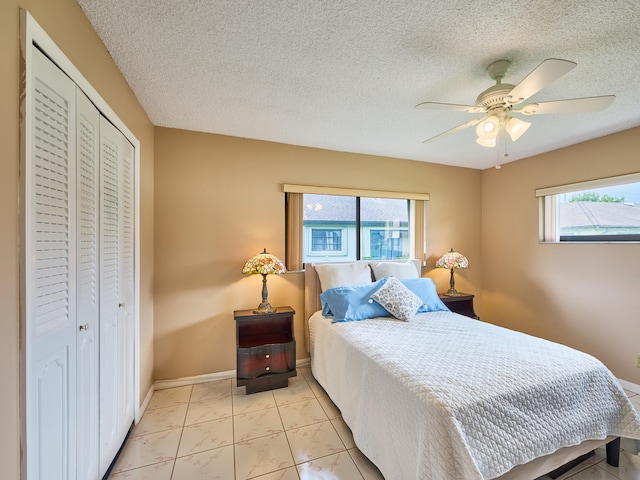 bedroom featuring ceiling fan, multiple windows, a closet, and a textured ceiling