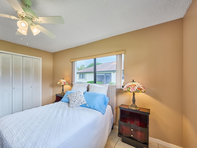 tiled bedroom with ceiling fan, a textured ceiling, and a closet