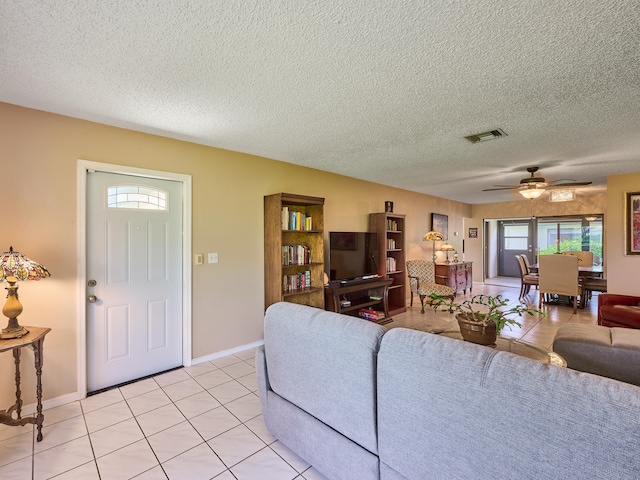 living room featuring a textured ceiling, ceiling fan, and light tile patterned flooring