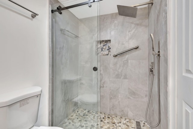 bathroom with a shower with door and toilet