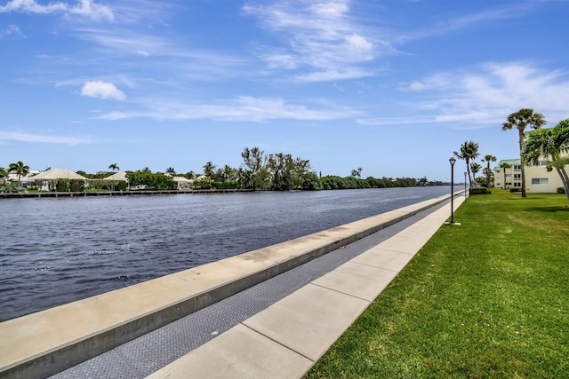 view of dock with a water view and a lawn