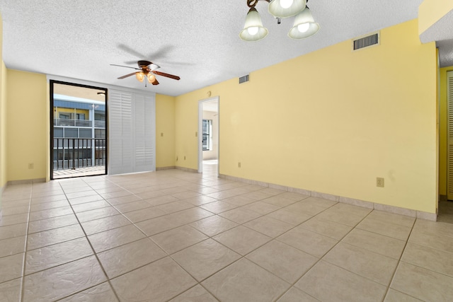 tiled empty room featuring expansive windows, a textured ceiling, and ceiling fan