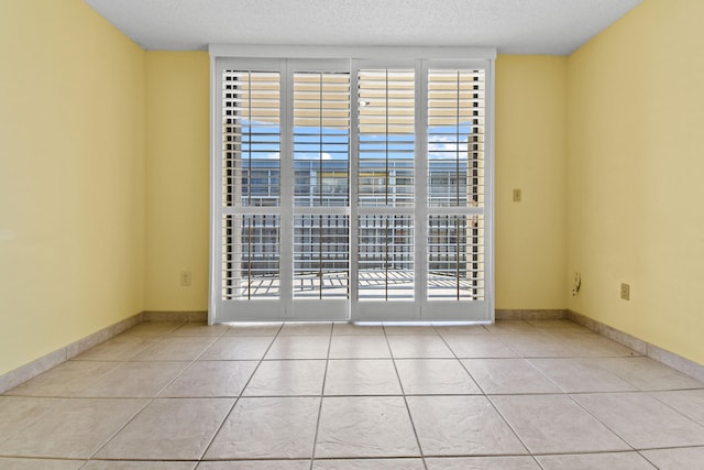 spare room with light tile patterned flooring and a textured ceiling