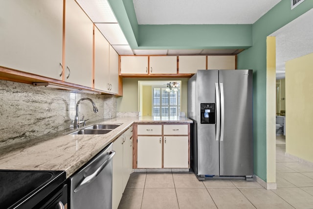 kitchen with white cabinets, appliances with stainless steel finishes, sink, and light tile patterned floors