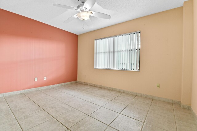 empty room featuring light tile patterned flooring, a textured ceiling, and ceiling fan