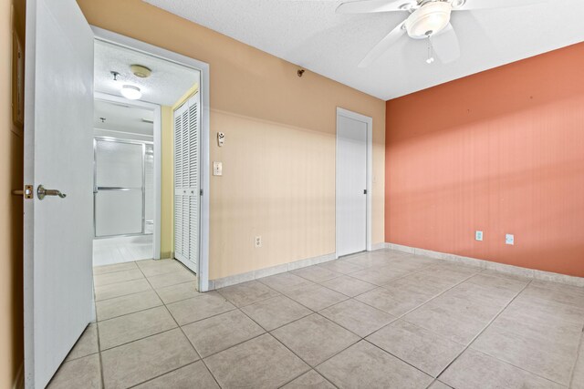 spare room featuring ceiling fan, a textured ceiling, and light tile patterned floors